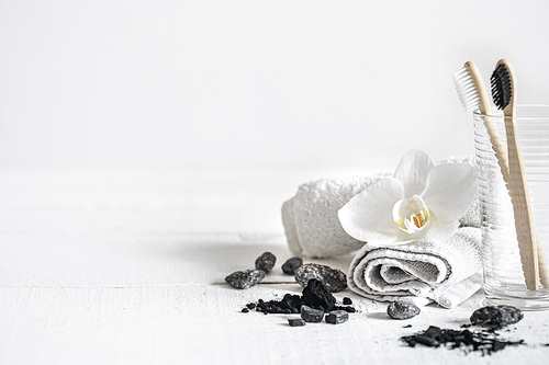 Still life with organic bamboo brushes and activated carbon powder and an orchid flower as a decorative element. Oral hygiene and dental care.