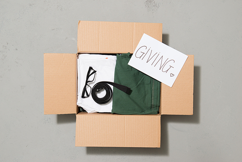 Donation box with clothes isolated on gray