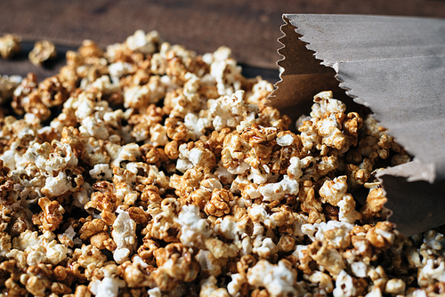 fresh caramel popcorn in a paper bag on wooden table