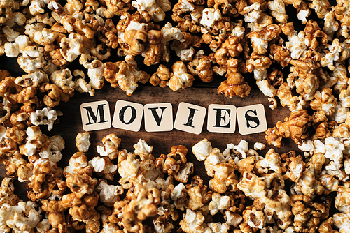 fresh popcorn background with MOVIES word on a wooden table