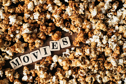 fresh popcorn background with MOVIES word on a wooden table