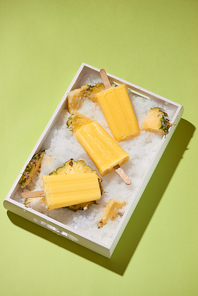 Yellow fruit popsicles on a tray top view, summer mood