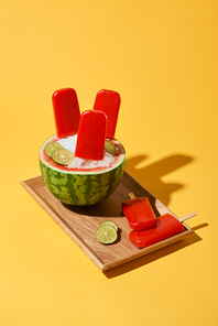 Watermelon popsicle on wood tray over yellow background