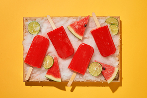 Watermelon popsicles and sliced lemon on ice filled tray