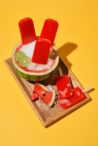 Watermelon popsicle and sliced watermelon on wood tray top view