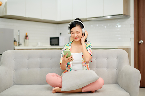 Young woman listening to music while relaxing on sofa at home