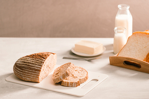 Bread on plate holder surrounded by butter and milk on white table close-up