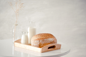 Glass bottle of milk with bread on wooden tray isolated on white for food and healthy concept. with copy space for text