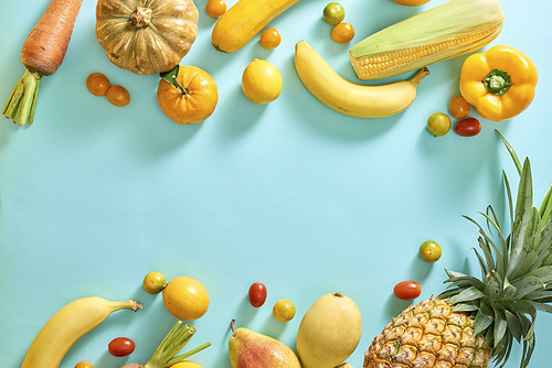 Collection of fresh yellow fruit and vegetables on the light blue background