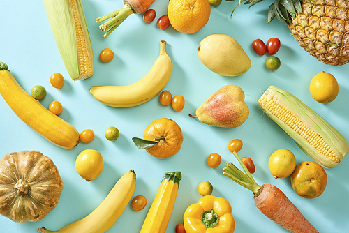 Collection of fresh yellow fruit and vegetables on the light blue background