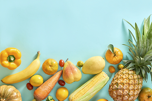 Collection of fresh yellow fruit and vegetables on the light blue background