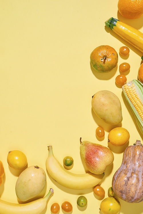 Collection of fresh yellow fruit and vegetables on the light yellow background