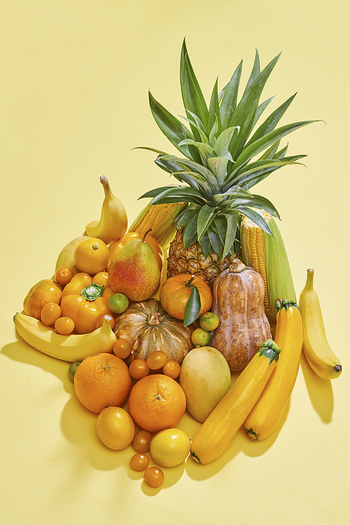 Collection of fresh yellow fruit and vegetables on the blue background