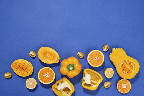 Collection of fresh yellow fruit and vegetables on the blue background