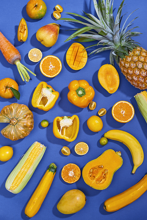 Collection of fresh yellow fruit and vegetables on the blue background