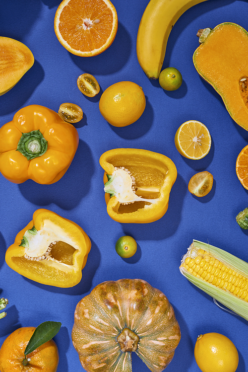 Collection of fresh yellow fruit and vegetables on the blue background