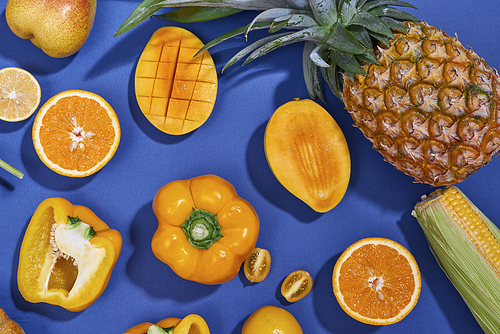 Collection of fresh yellow fruit and vegetables on the blue background