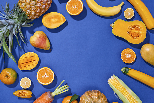 Collection of fresh yellow fruit and vegetables on the blue background