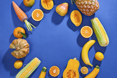 Collection of fresh yellow fruit and vegetables on the blue background