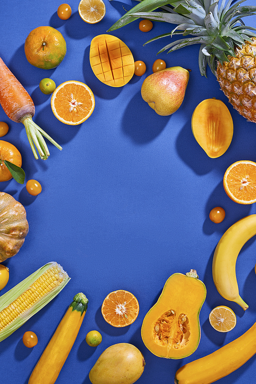 Collection of fresh yellow fruit and vegetables on the blue background