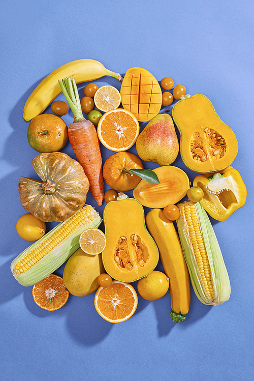 Collection of fresh yellow fruit and vegetables on the blue background