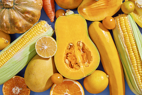 Collection of fresh yellow fruit and vegetables on the blue background