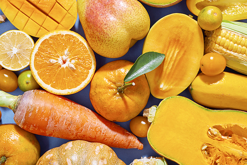 Collection of fresh yellow fruit and vegetables on the blue background