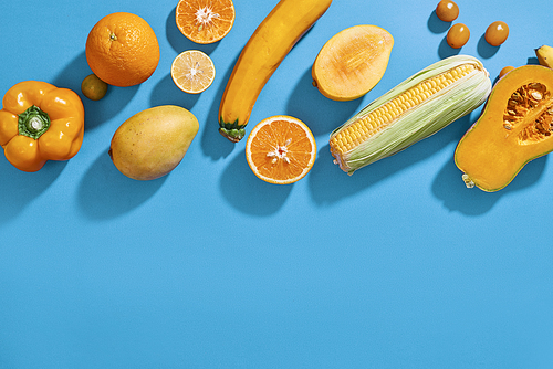 Collection of fresh yellow fruit and vegetables on the blue background