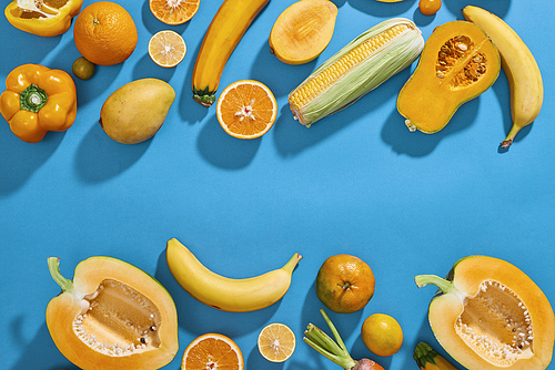 Collection of fresh yellow fruit and vegetables on the blue background