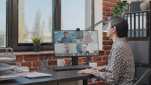 Business woman talking to colleagues on online video call, doing teamwork on project planning. Person using remote video conference to have conversation about development. Teleconference