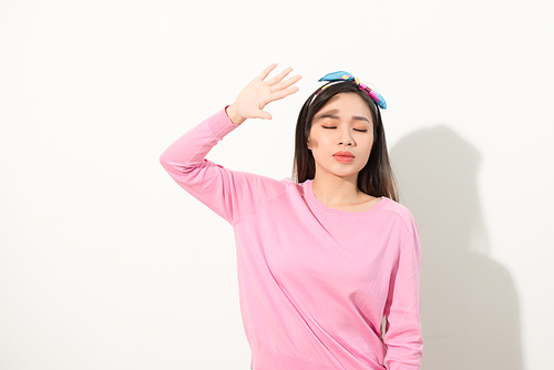 Portrait of a beautiful Asian girl covering face by hand of bright sun light. woman in a pink dress protecting her face from solar light. Skin care or beauty concept