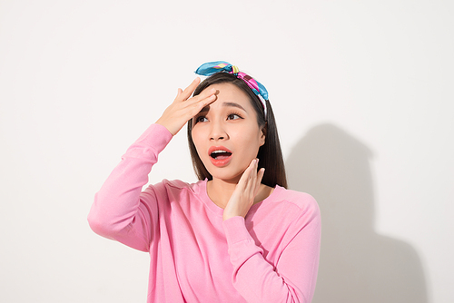 Portrait of a beautiful Asian girl  covering face by hand of bright sun light. Woman in a pink dress protecting her face from solar light. Skin care or beauty concept