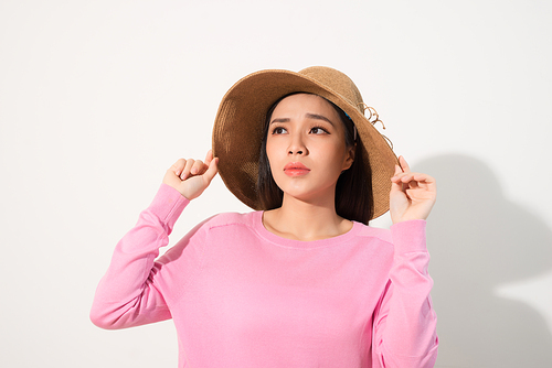 Closeup of sad pensive young woman and straw hat thinking and feeling unhappy over white background