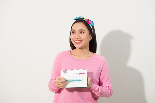 Portrait of a smiling young girl checking her periods according to calendar isolated over white background