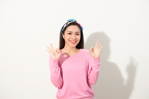 Young pretty asian woman showing OK sign with two hands. Close up portrait. Isolated on the white background.
