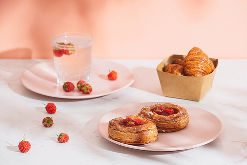 Sweet summer dessert, homemade baked mini croissants, served with cold raspberry cider, fresh raspberries. On a white marble table, copy space top view