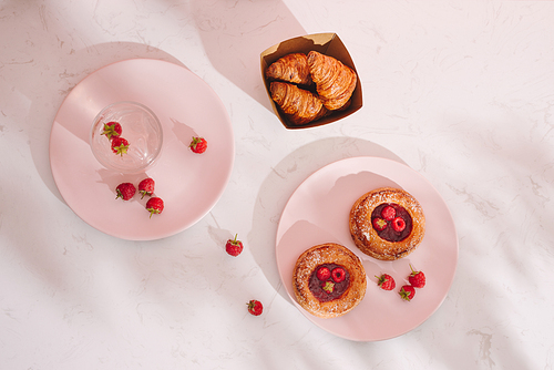 Sweet summer dessert, homemade baked mini croissants, served with cold raspberry cider, fresh raspberries. On a white marble table, copy space top view