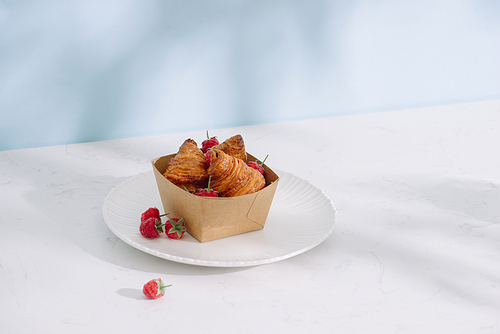 Croissant with raspberries. Raspberries with croissants. Croissant on a light background with raspberry berries