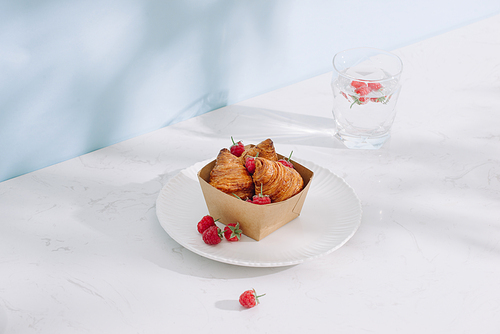 Croissant with raspberries. Raspberries with croissants. Croissant on a light background with raspberry berries