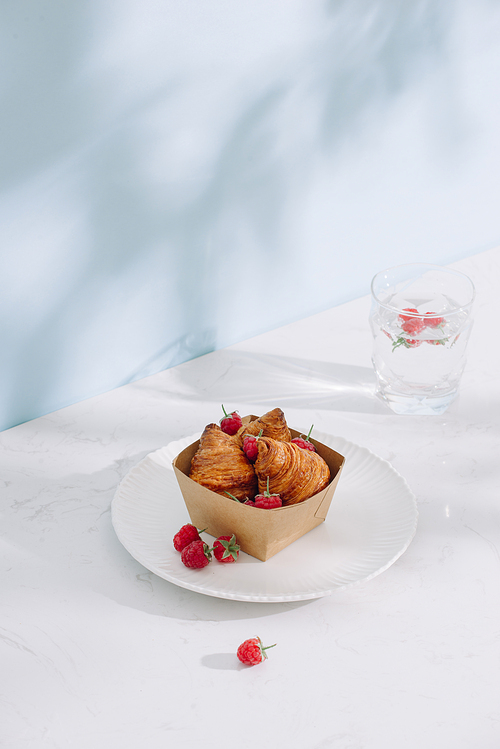 Croissant with raspberries. Raspberries with croissants. Croissant on a light background with raspberry berries