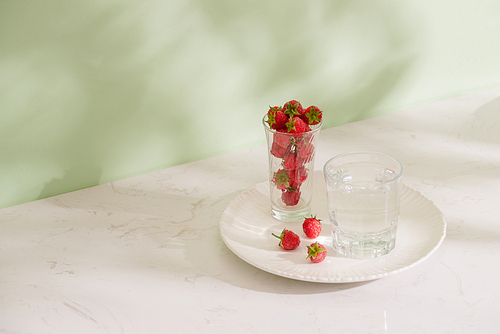 Fresh raspberries in a glass beaker isolated on light background