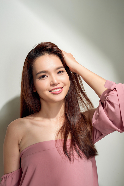 young girl posing against a concrete wall, dressed in pink, hard light and shadows