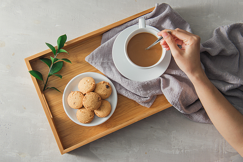 close up of cookie and hand stirring cup of tea/coffee