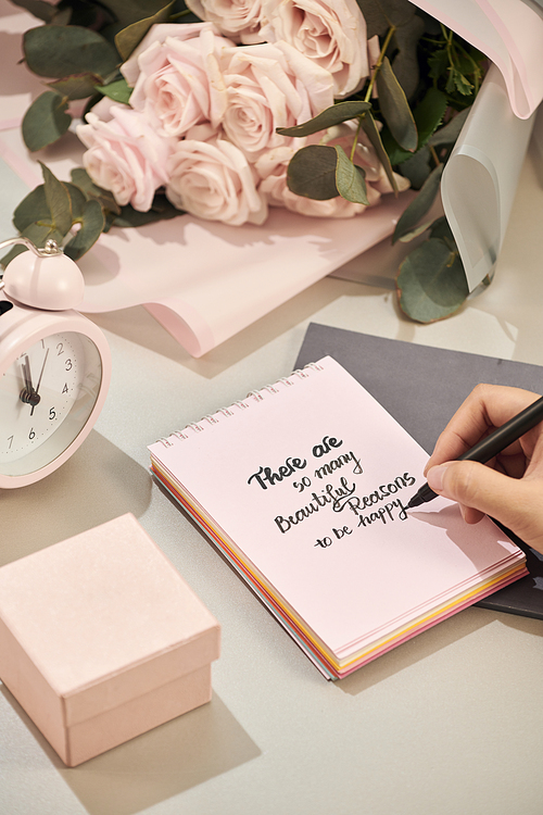 Woman hands holding pen, ready to write. Pink rose,  pen and gift with pink heart on white table. Love concept. Saint Valentine's Day concept. Mother's day concept.