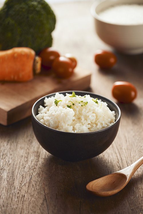 Grains of rice in a wooden bowl and ingredients for a vegetarian recipe - healthy eating concept