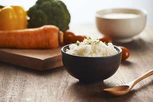 Grains of rice in a wooden bowl and ingredients for a vegetarian recipe - healthy eating concept