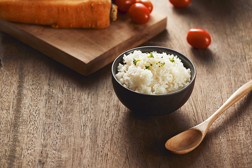 Grains of rice in a wooden bowl and ingredients for a vegetarian recipe - healthy eating concept