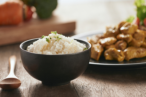 White rice with curry and chicken in black plate on wooden table