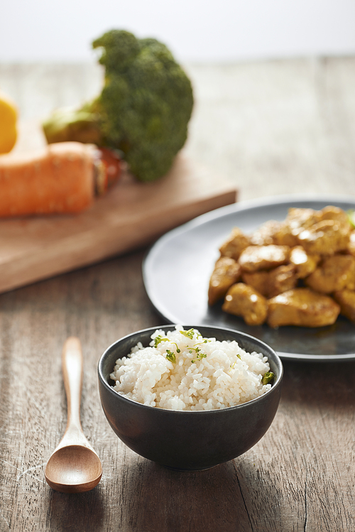 White rice with curry and chicken in black plate on wooden table