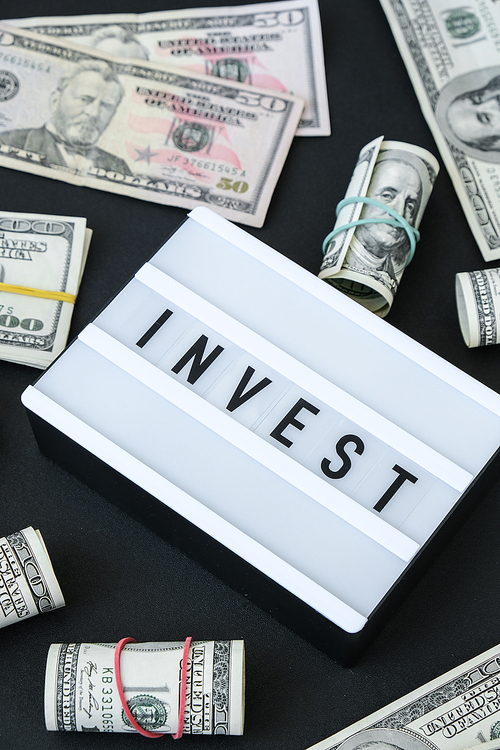 Lightbox board with word INVEST in black letters around US dollar banknotes. Money, Business, finance, investment, saving. Cash bill. Business budget of wealth and prosperity finance. Passive income